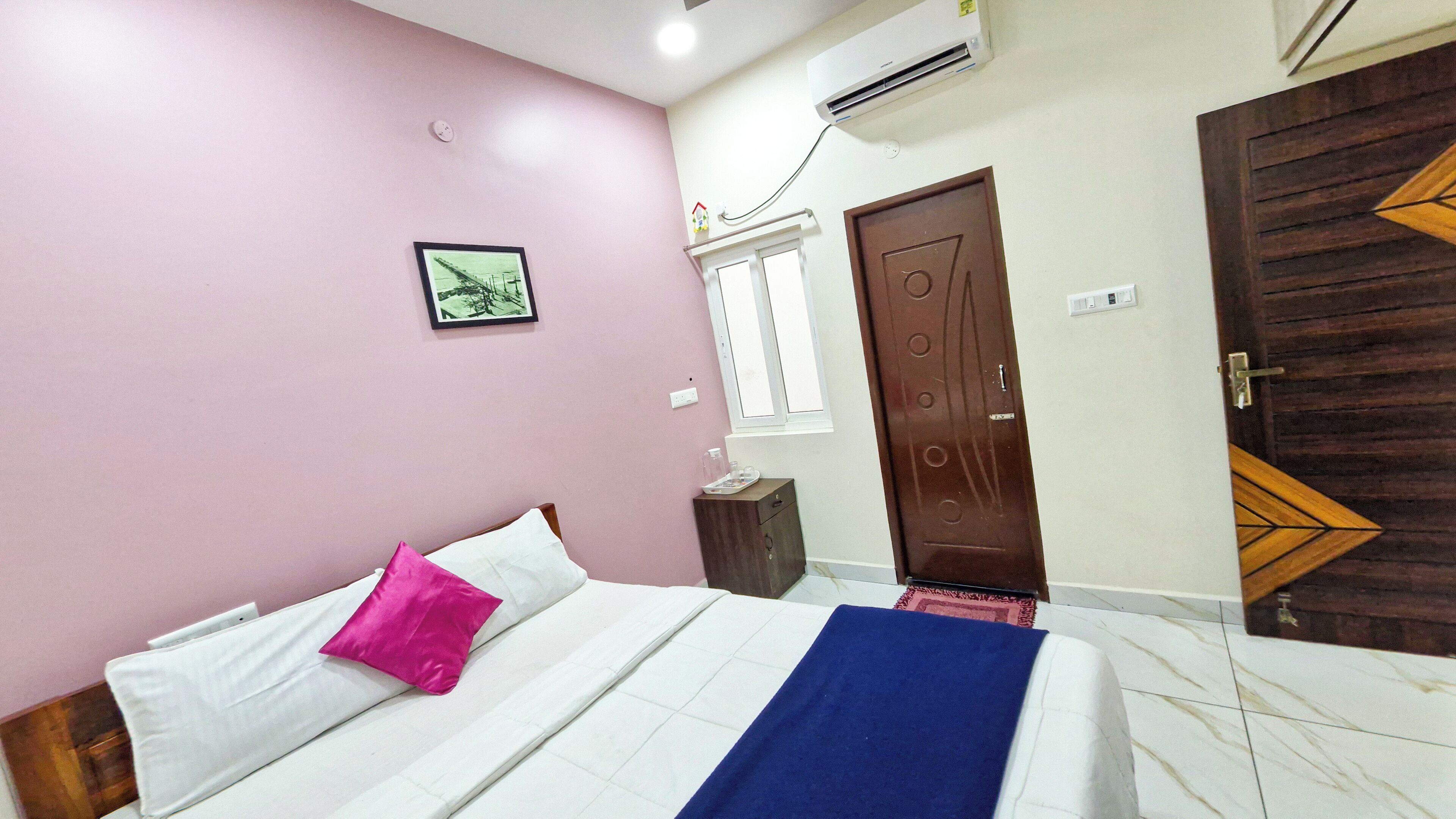 A bedroom with a bed, a nightstand, a window, and a door.