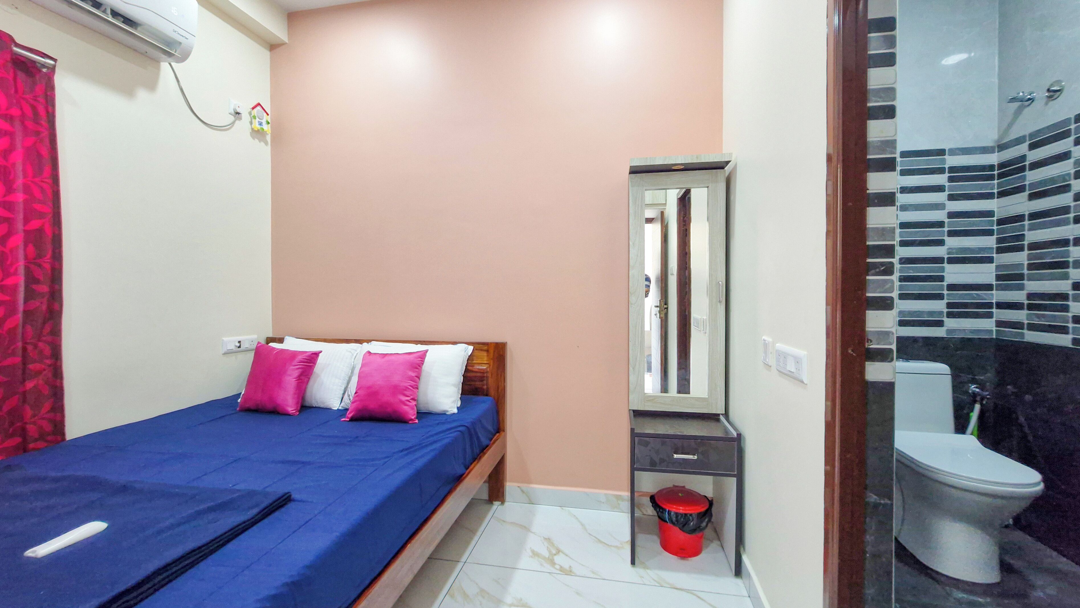 A small bedroom with a bed, a bedside table, a mirror, and a bathroom with a toilet and sink.