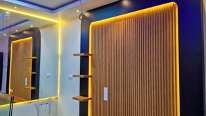 A modern bathroom with a large mirror, wooden panel wall, and built-in shelves.