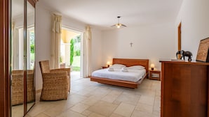 A bedroom with a bed, a wooden desk, wicker chairs, and a large window with curtains. - La Pimaleanne by Interhome (Roquefort les Pins)