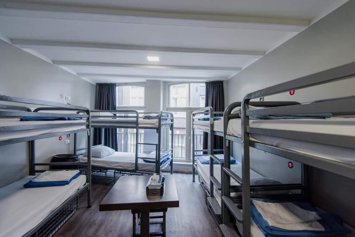 Une chambre de dortoir avec des lits superposés, une table et une fenêtre.
