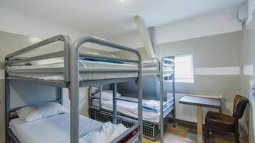 A bunk room with three bunk beds, a desk, and a chair.
