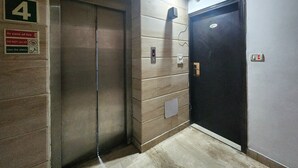 An elevator with a green sign indicating the floor number 4, a fire safety sign, and a door with a security lock. - Hotel Florence Legacy (New Delhi)