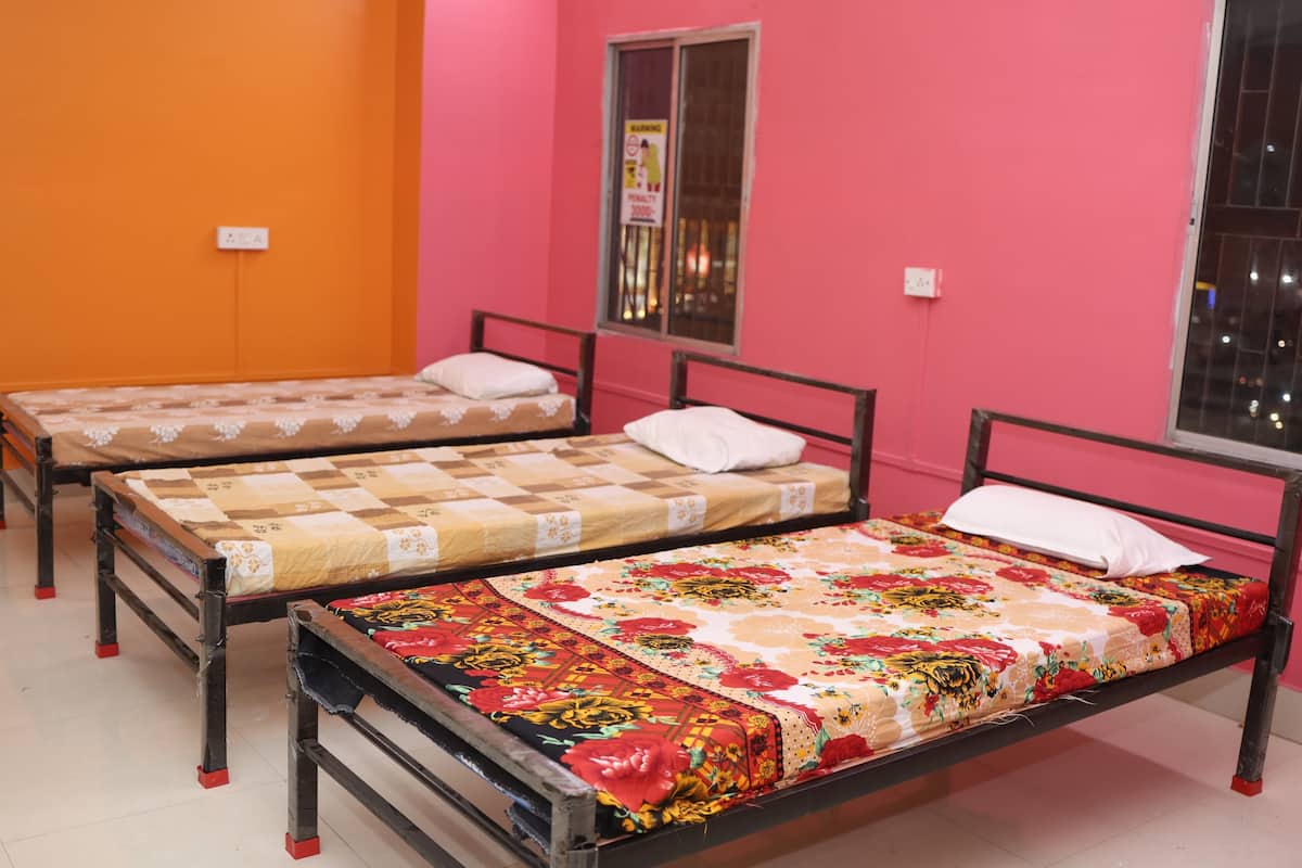 Three single beds in a room with pink walls and a window.