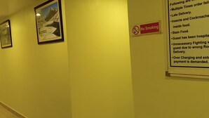 A hallway with framed pictures on the wall and a 'No Smoking' sign. - Sacred Stay (Guwahati)