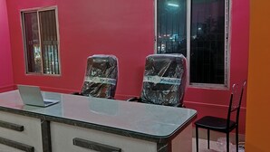 A conference room with a glass table, two chairs, a laptop, and a window with bars. - Sacred Stay (Guwahati)