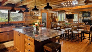 Una cocina rústica con una isla grande, armarios de madera y una chimenea de piedra.