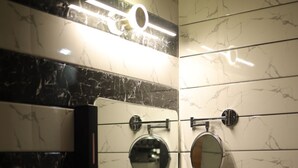 A modern bathroom with a white sink, two round mirrors, and a black and white tiled backsplash. - GP Palace (Lucknow)