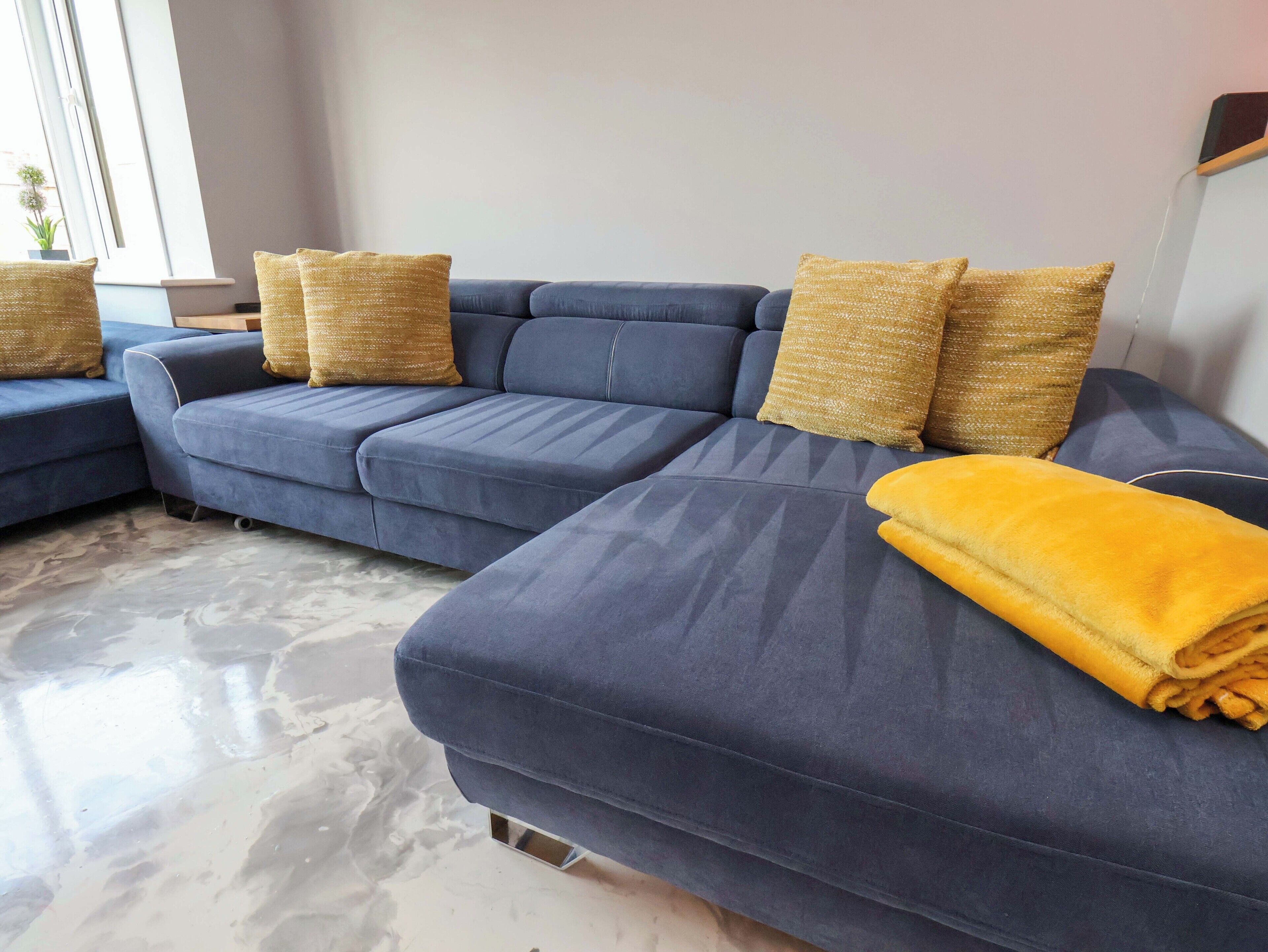 A modern living room with a sectional sofa, a small side table, and a yellow throw blanket.