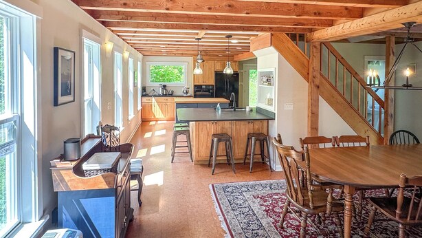Una cocina amplia con vigas de madera, una isla central, taburetes de bar y una mesa de comedor con sillas.