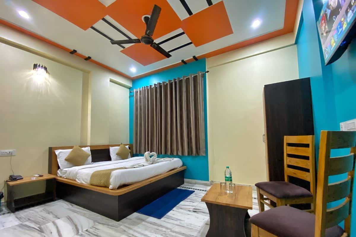 A hotel room with a bed, a desk, a chair, a ceiling fan, and curtains.