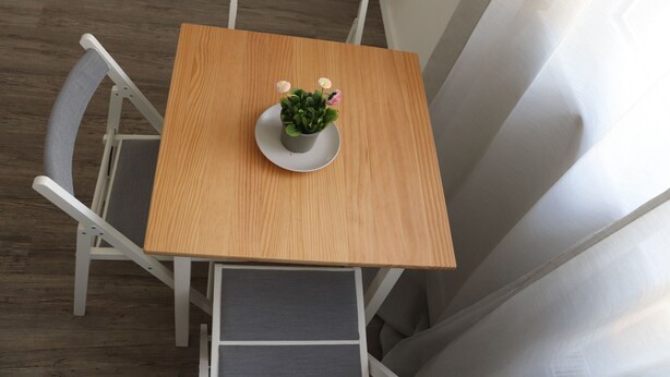Une table en bois avec une assiette blanche et une petite plante en pot.