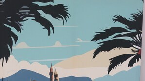 Une affiche représentant une ville côtière, avec une table en bois et une télécommande.