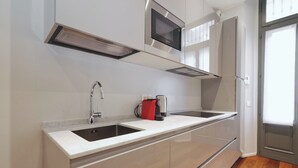 A modern kitchen with a double sink, stainless steel appliances, and a wooden floor. - Stylish 2BR flat in the city centre (Milan)