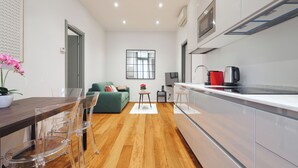 A modern kitchen with white cabinets, a wooden countertop, and a built-in oven. There is a dining area with a wooden table and clear chairs. - Stylish 2BR flat in the city centre (Milan)