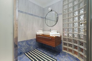 A bathroom with a wooden vanity, a round mirror, and a glass shower enclosure.