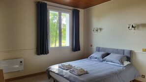 Quarto com cama, cortinas, janela e luminárias fixadas na parede.