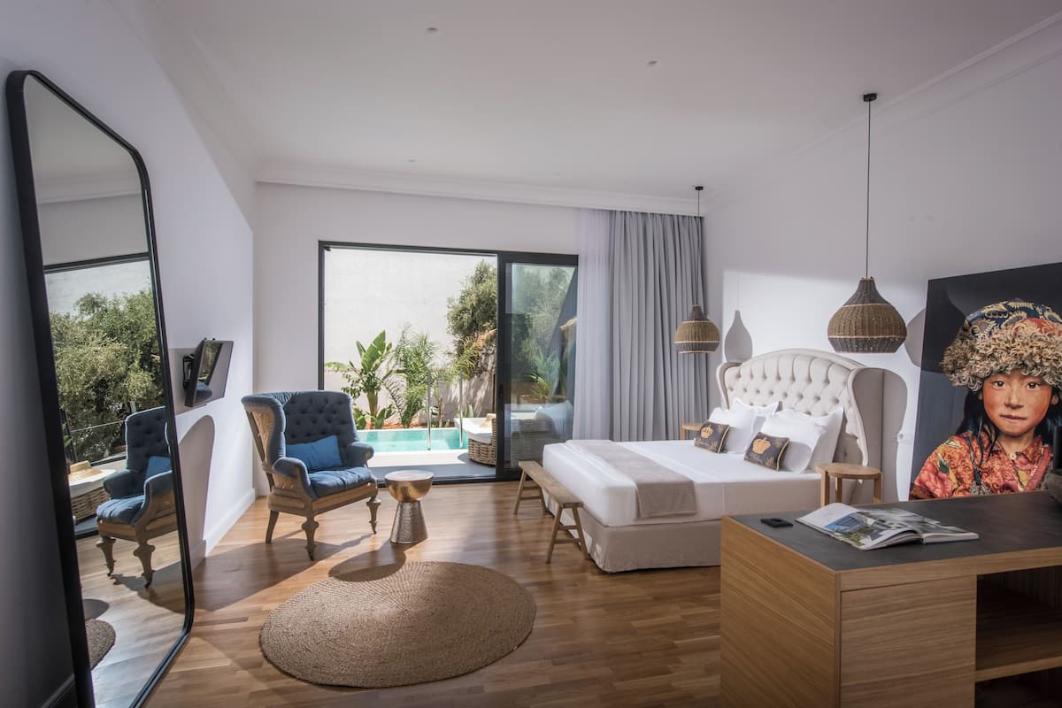 A modern bedroom with a large bed, a desk, and a view of a pool.
