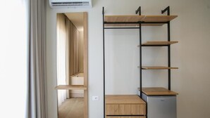A modern room with a built-in wardrobe, a small refrigerator, and a sliding door leading to a bathroom. - ReiVal Hotel (Vlorë)
