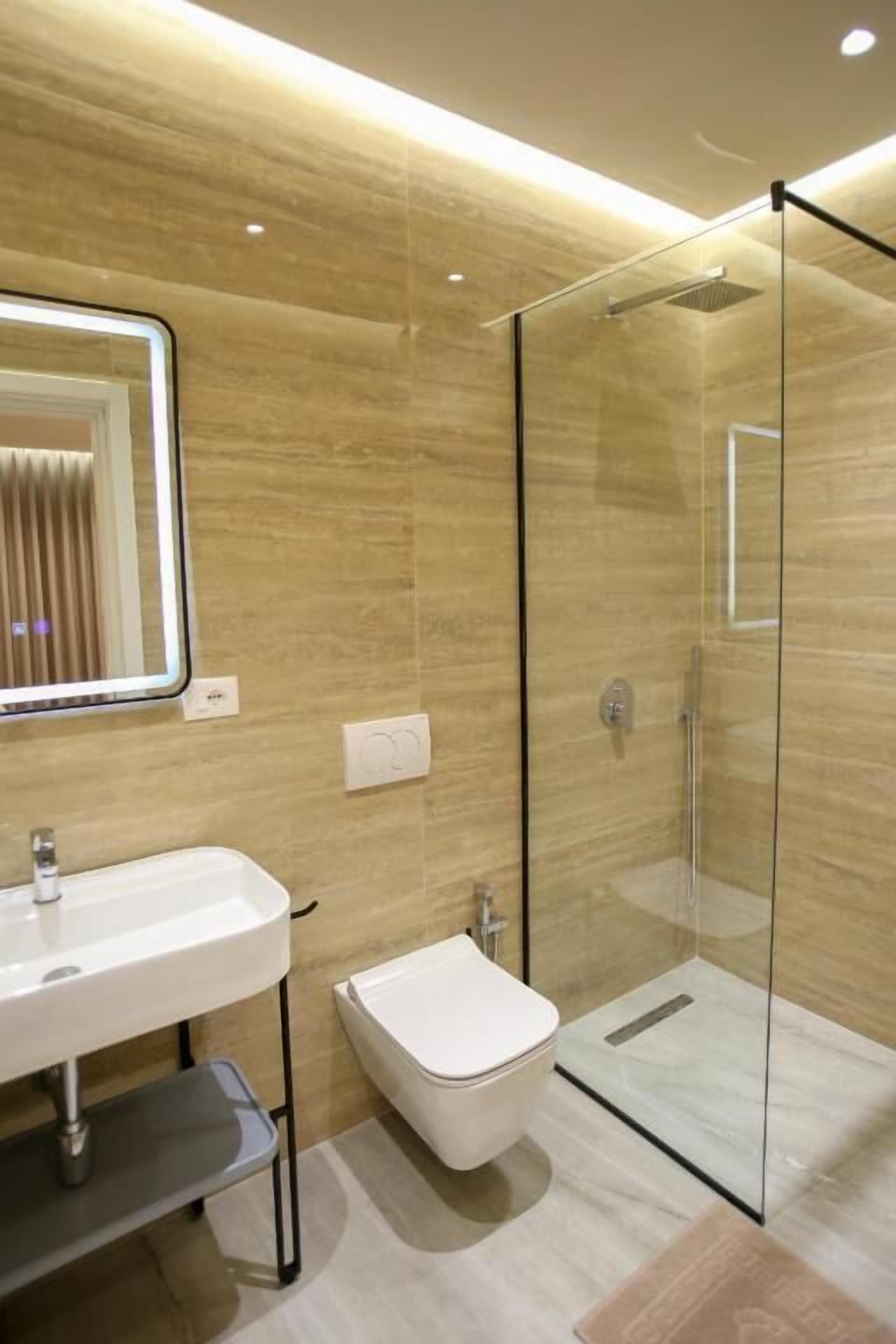 A modern bathroom with a glass shower enclosure, a pedestal sink, and a toilet.