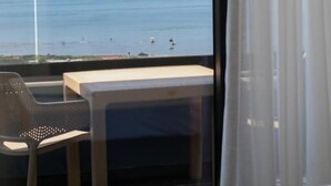 A hotel room with a view of the sea, a bed, a small table, and a chair. - ReiVal Hotel (Vlorë)
