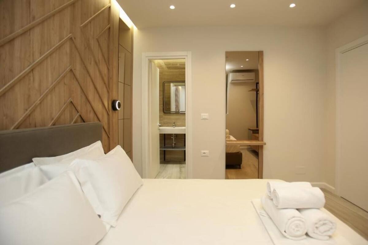 A hotel room with a bed, a bathroom visible through an open door, and a neatly made bed with towels.
