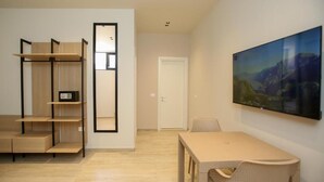 A minimalist room with a wooden floor, a white door, a large framed picture, and a simple table with chairs. - ReiVal Hotel (Vlorë)