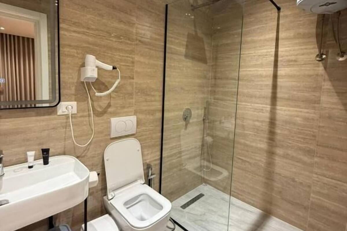A modern bathroom with a glass-enclosed shower, a white sink, and a toilet.