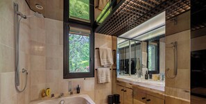 A modern bathroom with a large window, a bathtub, a shower, and a vanity with a mirror.