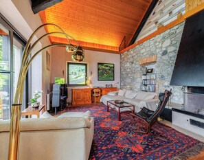 A living room with a stone wall, a fireplace, a sofa, a coffee table, and a bookshelf.