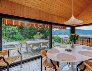 Un coin repas avec une table ronde, des chaises et une vue sur un lac et des montagnes.
