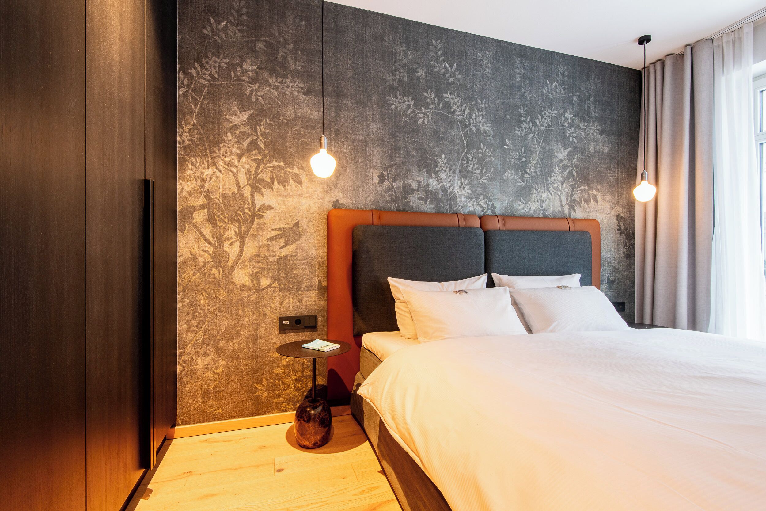 A modern hotel room with a large bed, a small side table, and a decorative vase.