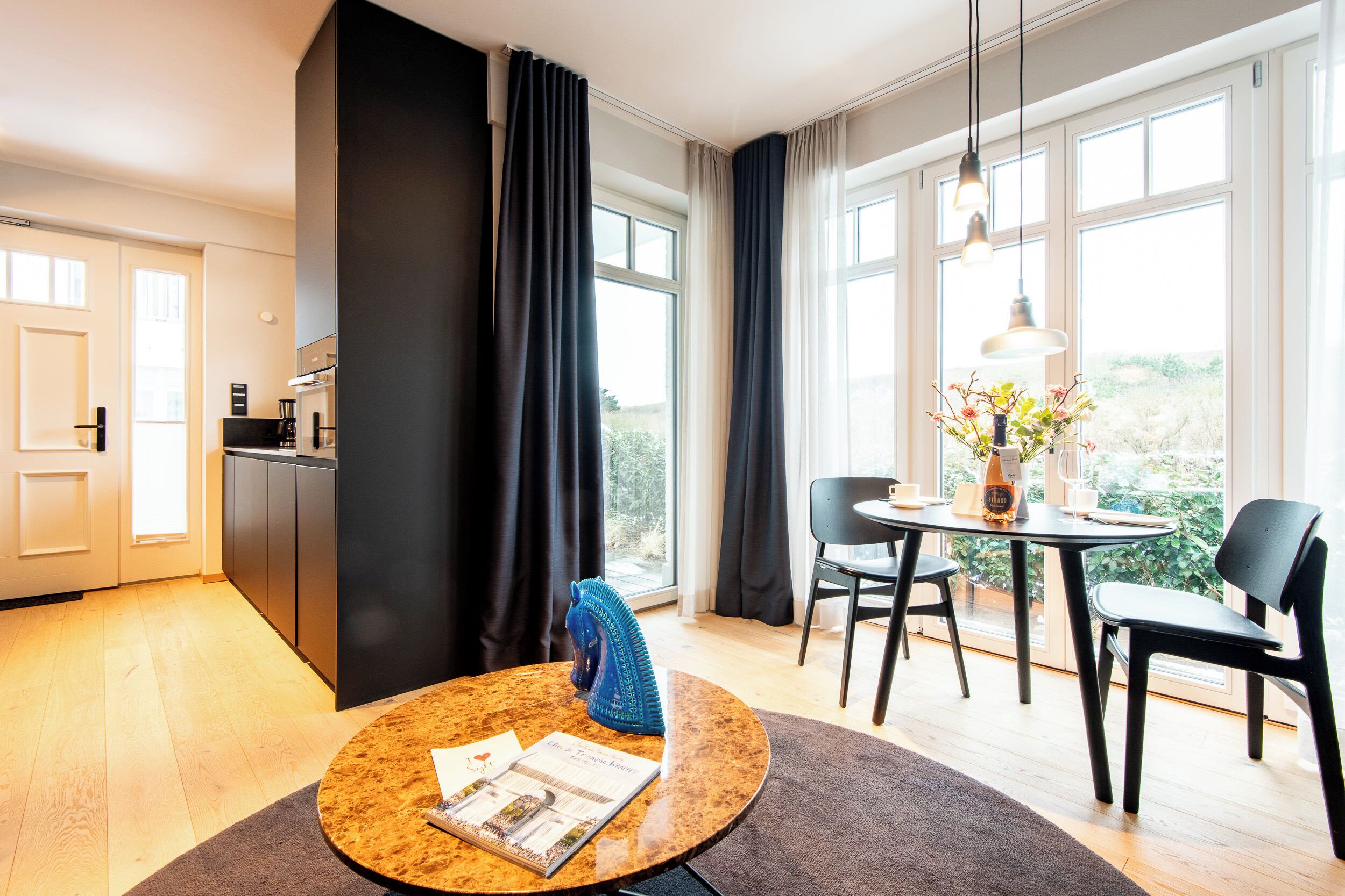 Ein modernes Hotelzimmer mit Essbereich, einer Küche und großen Fenstern mit Blick.