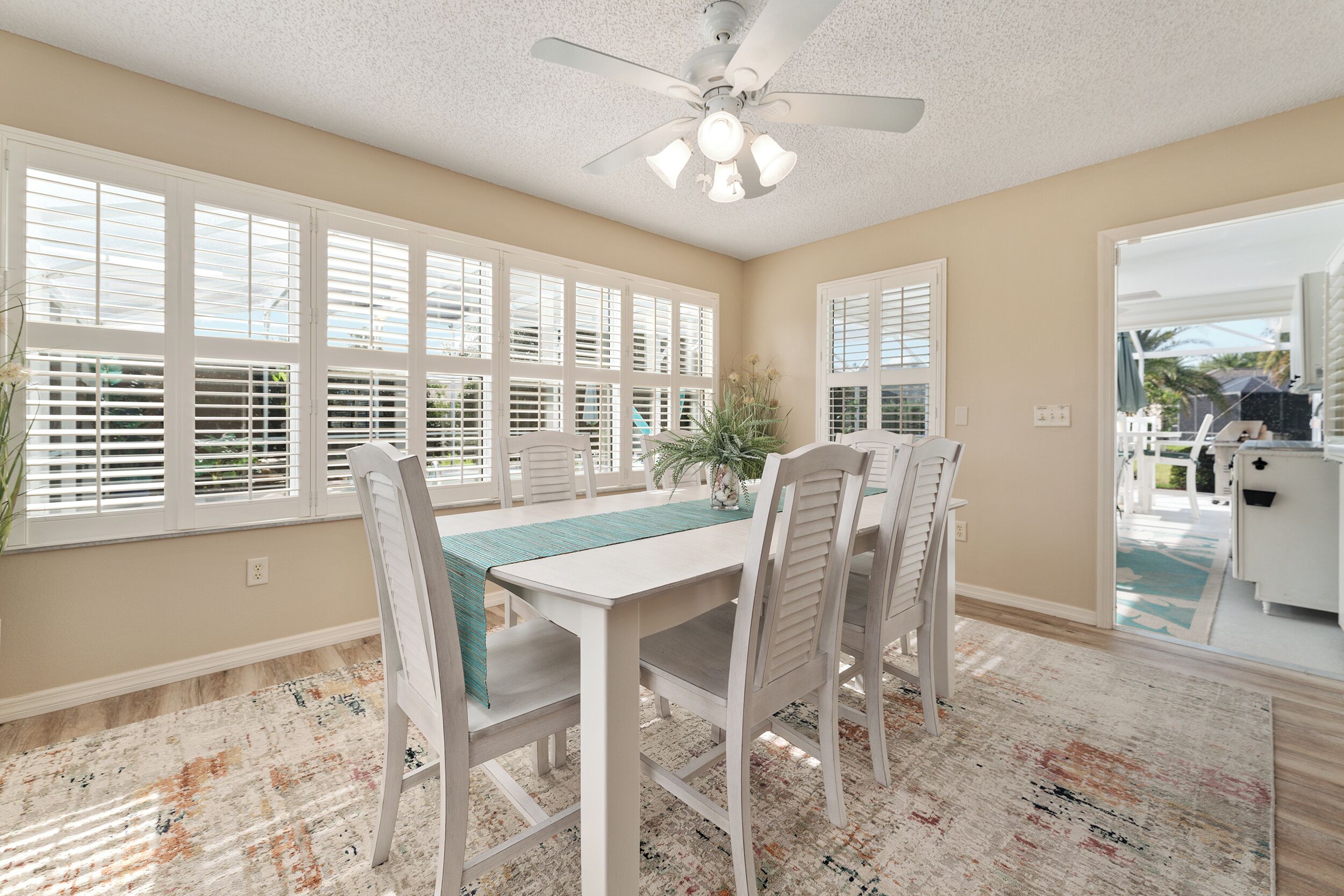 A dining area with a white table, chairs, and a ceiling fan.