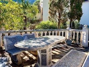 Een stenen bank en tafel staan in een tuin met een witte balustrade.