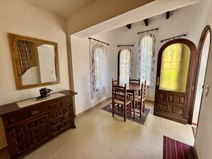 A dining area with a wooden table and chairs, a mirror, and a cabinet.