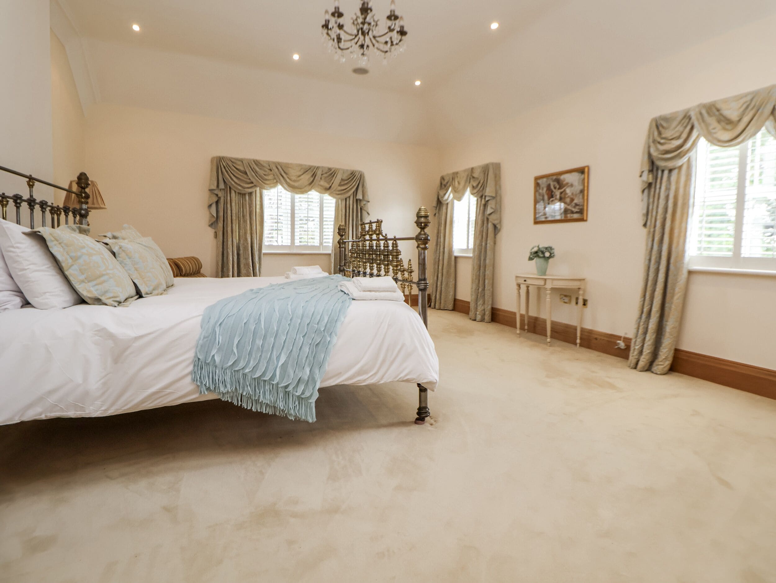 A bedroom with a large bed, a chandelier, and curtains.
