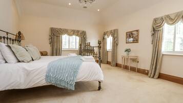A bedroom with a large bed, a chandelier, and curtains.