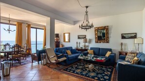 A living room with a large window, blue sofas, a chandelier, and a patterned rug. - Casa Annibale con Vista Mare by Wonderful Italy (Palermo)
