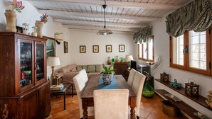 A dining area with a wooden table, chairs, and a cabinet. There are framed pictures on the wall and a window with curtains. - Casa Annibale con Vista Mare by Wonderful Italy (Palermo)