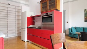 Une cuisine de taille réduite avec des meubles de rangement rouges, un four en acier inoxydable et un réfrigérateur blanc.