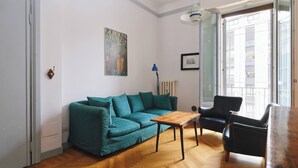 Un salon avec un canapé de couleur turquoise, une table basse en bois et un fauteuil noir.