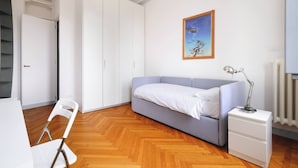Une chambre à coucher avec un lit, une table de chevet, une chaise, une armoire et un tableau accroché au mur.