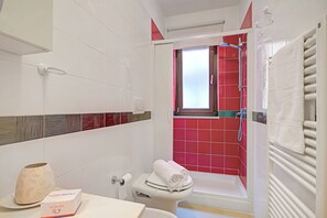 A bathroom with white tiles, a red shower area, a white toilet, and a towel rack. - Viadelmare Apartment Monopoli 200m Sea (Monopoli)