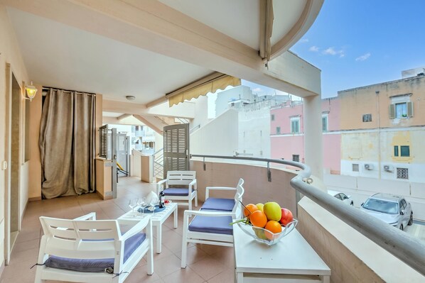 Ein Balkon mit Tisch, Stühlen, Obstschale und Blick auf Gebäude.