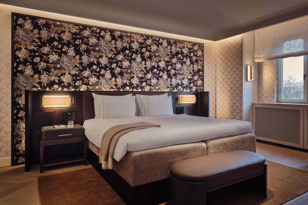 A modern bedroom with a large bed, two bedside tables, a nightstand, a bench, and a decorative floral headboard.