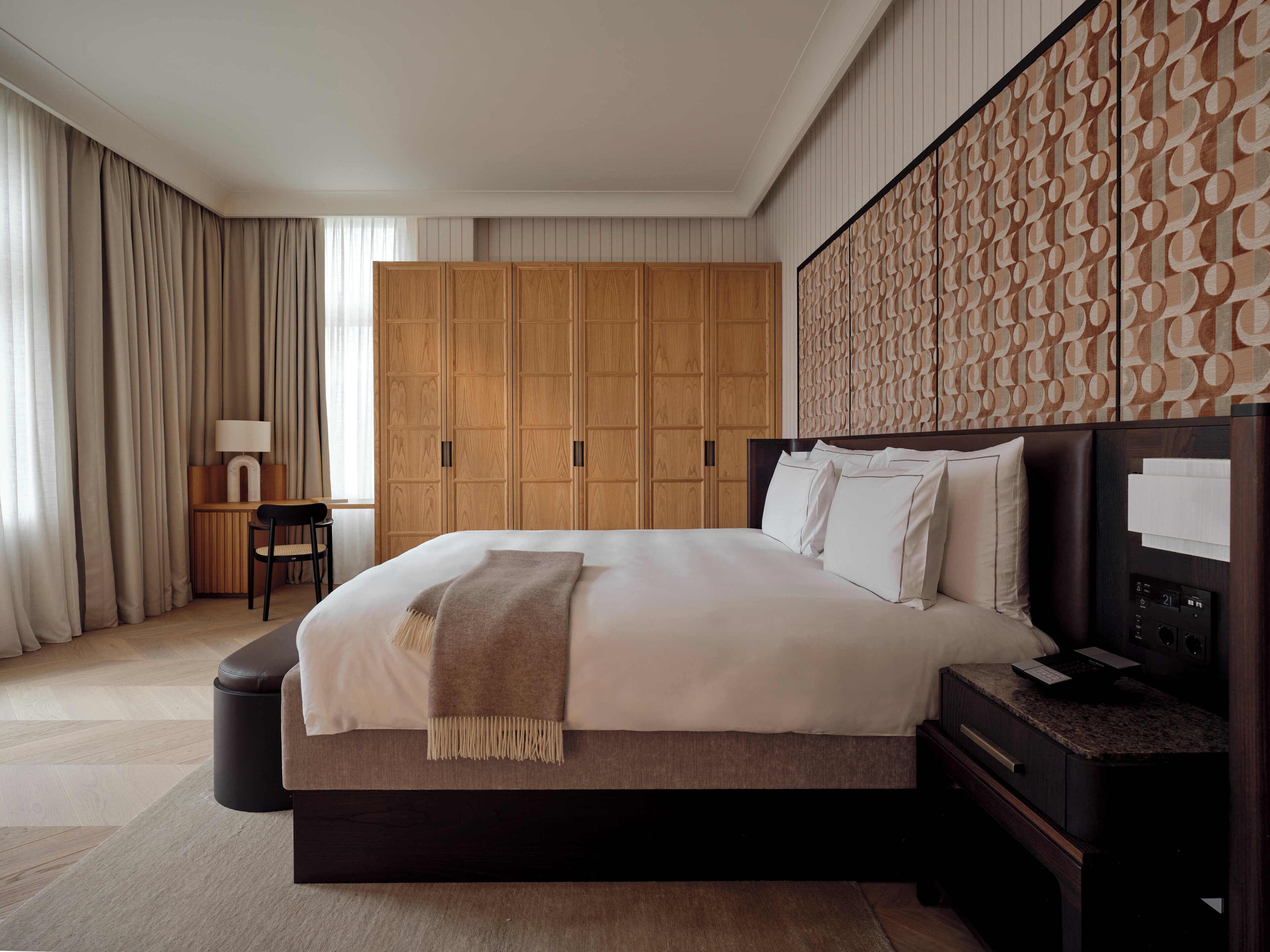 Un dormitorio moderno de hotel con una cama grande, un armario de madera y un panel decorativo en la pared.