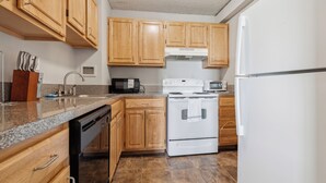 A kitchen with wooden cabinets, a white stove, a microwave, and a dishwasher. - Legacy at Imperial Village 1108 I 1 Bed 1 Bath (Ric hmond)