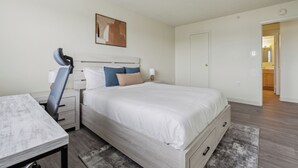 Une chambre à coucher avec un lit, un bureau, une chaise et une table de chevet.