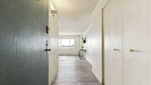 Un couloir avec un plancher en bois, des murs blancs et une fenêtre au fond.